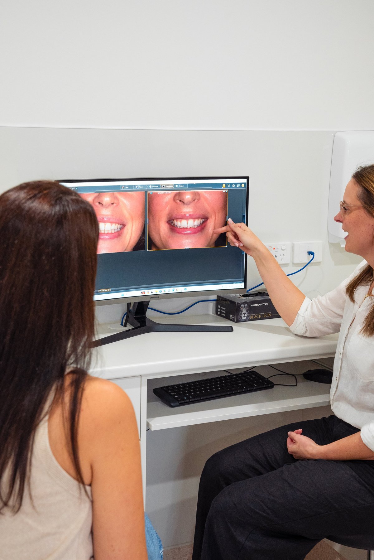 Dentist showing patient dental imaging on computer monitor displaying teeth closeups during consultation