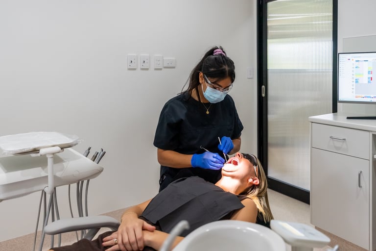 Dentist in mask and blue gloves examining patient in dental chair in modern clinic office