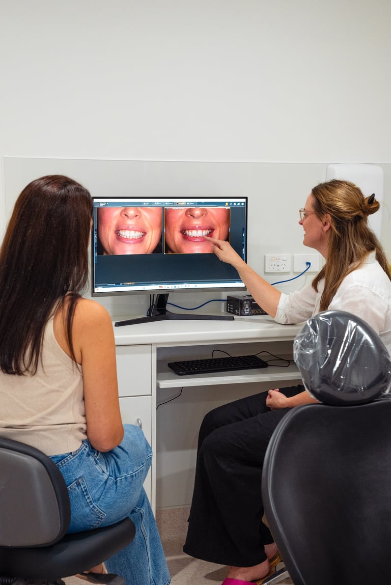 Dental professional and patient reviewing smile images on a computer monitor during an orthodontic consultation